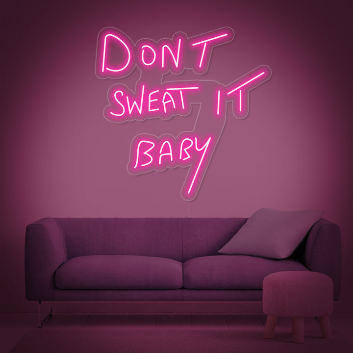 Stylized product view of the 'Dont Sweat it Baby' neon sign against a neutral wall.
