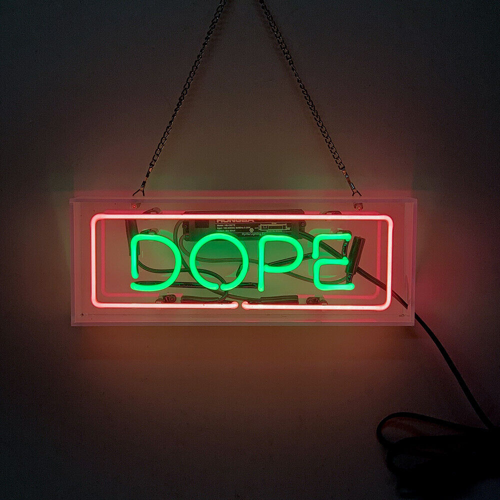 A glowing 'Dope' neon sign made of red glass tubes, encased within a clear, self-standing acrylic box and placed on a surface.