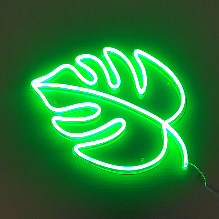 A glowing green neon sign depicting a leaf silhouette inside a box, mounted on a wall with power cord details.