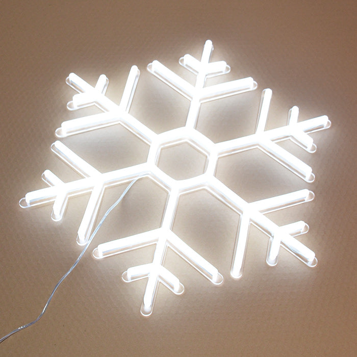 A glowing blue stylized snowflake neon sign, designed like a symbol for ice, mounted on a rustic wood plank wall.