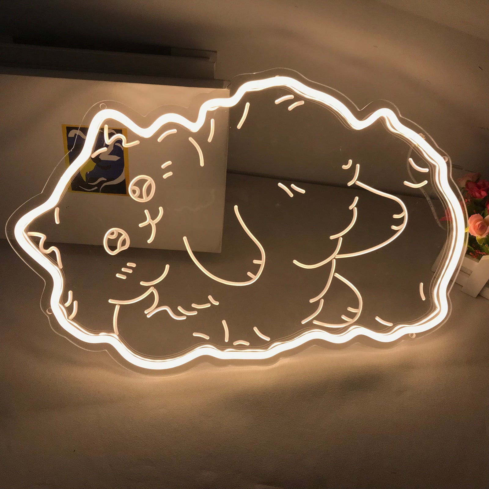 Unlit Fatty Cat mini neon sign showing its blue silicone tubing and clear acrylic backplate sitting on a wooden desk.