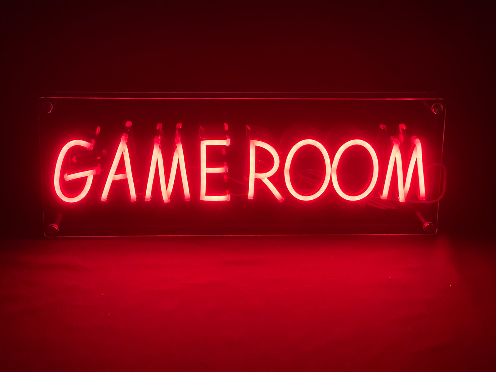 The "Game Room" neon sign with white text, positioned in a stylized gaming setup.