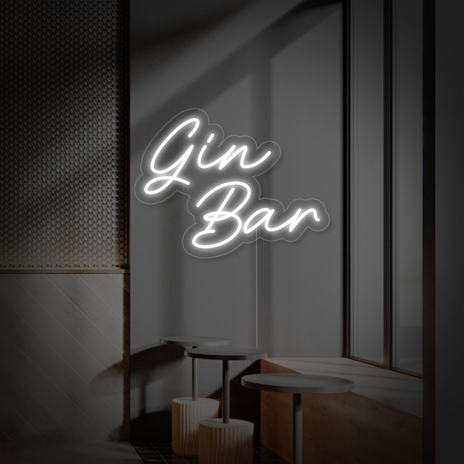 A Gin Bar neon sign with pink lettering mounted on a clear acrylic backing against a dark grey patterned wallpaper next to a shelf with glasses.