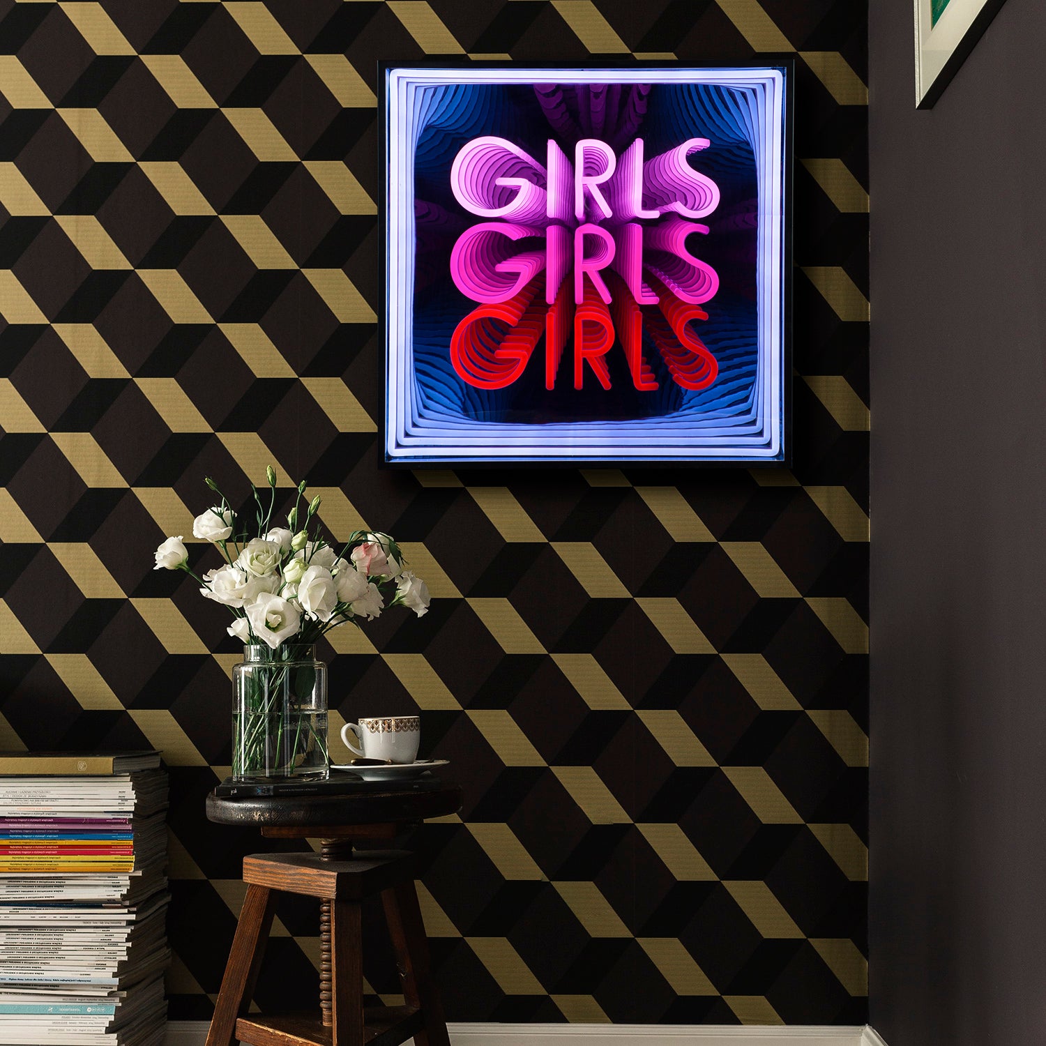 A detailed view of the fabricated infinity mirror sign showing the clear bent tubing spelling out 'GIRLS', complex internal reflections, and the light bleed onto the lower frame and dark surface.