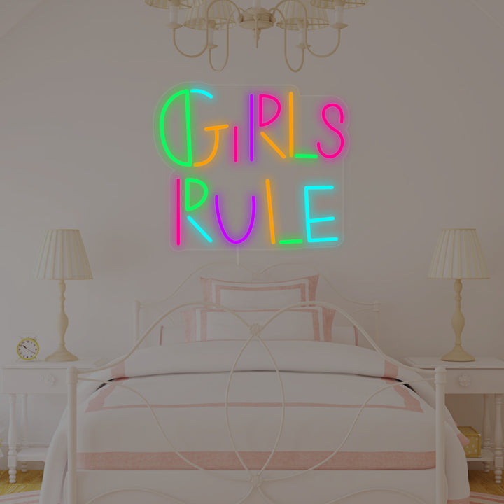 A close-up view of the 'Girls Rule' neon sign hanging on a pastel wall