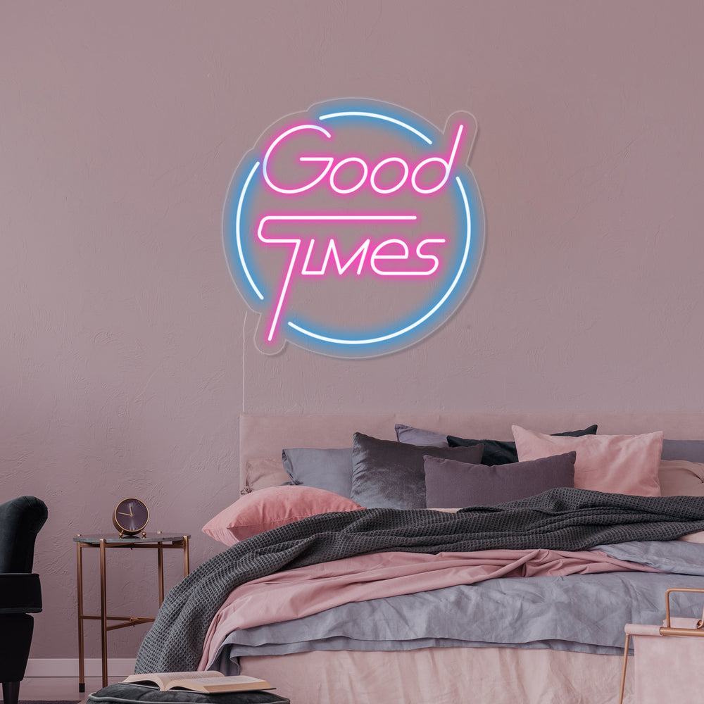 A vibrant 'Good Times' glowing neon sign in a cheerful font, mounted on an acrylic backboard within a stylish bedroom setting, providing warm ambient light.