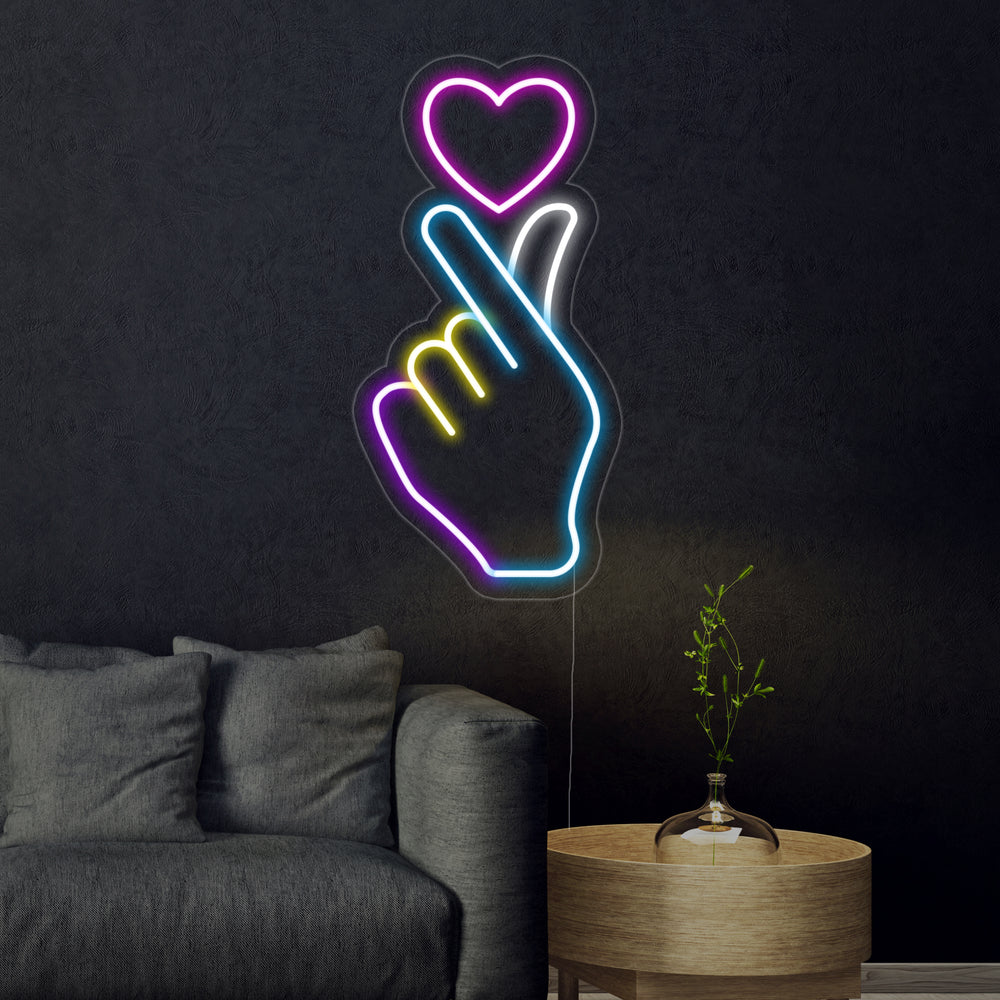 The 'Hand Heart' neon sign, glowing brightly on a dark textured wall, clearly showing the continuous tubing formed into the loving gesture.