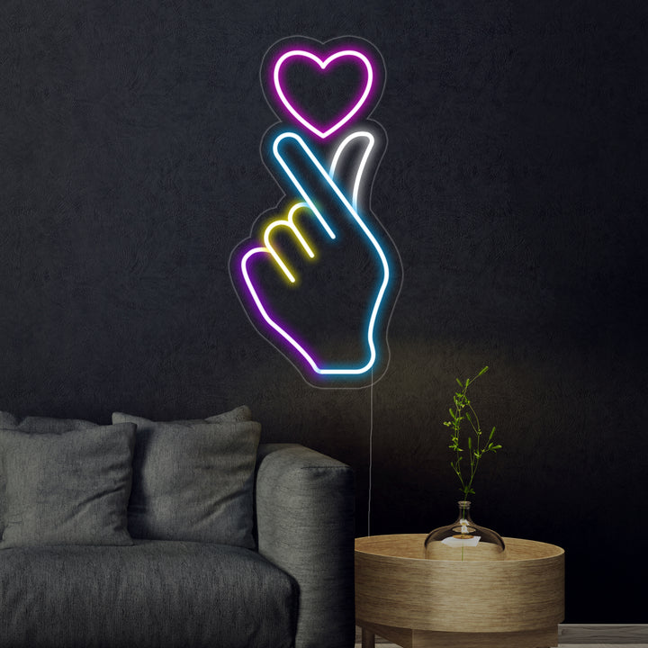 The 'Hand Heart' neon sign, glowing brightly on a dark textured wall, clearly showing the continuous tubing formed into the loving gesture.