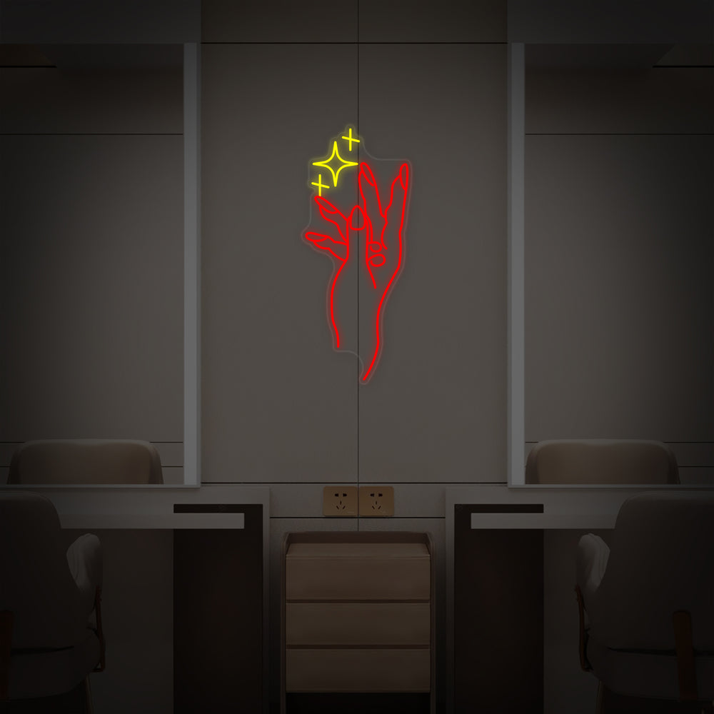 A vibrant neon sign for a nail salon, displaying a stylized hand with painted nails and a circular accent, mounted on a clear acrylic backing over a wall in a chic studio environment.