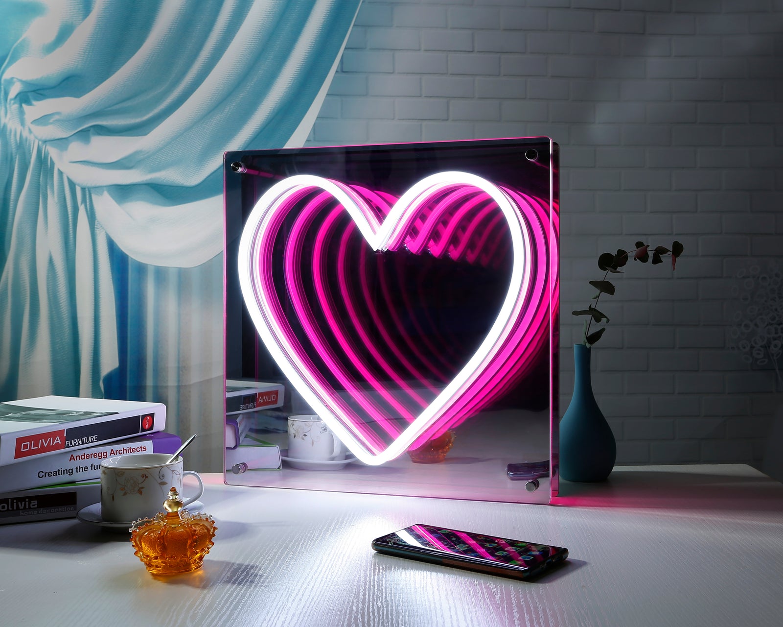 A glowing Hearts LED Infinity Neon Sign displayed on a desk with plants.
