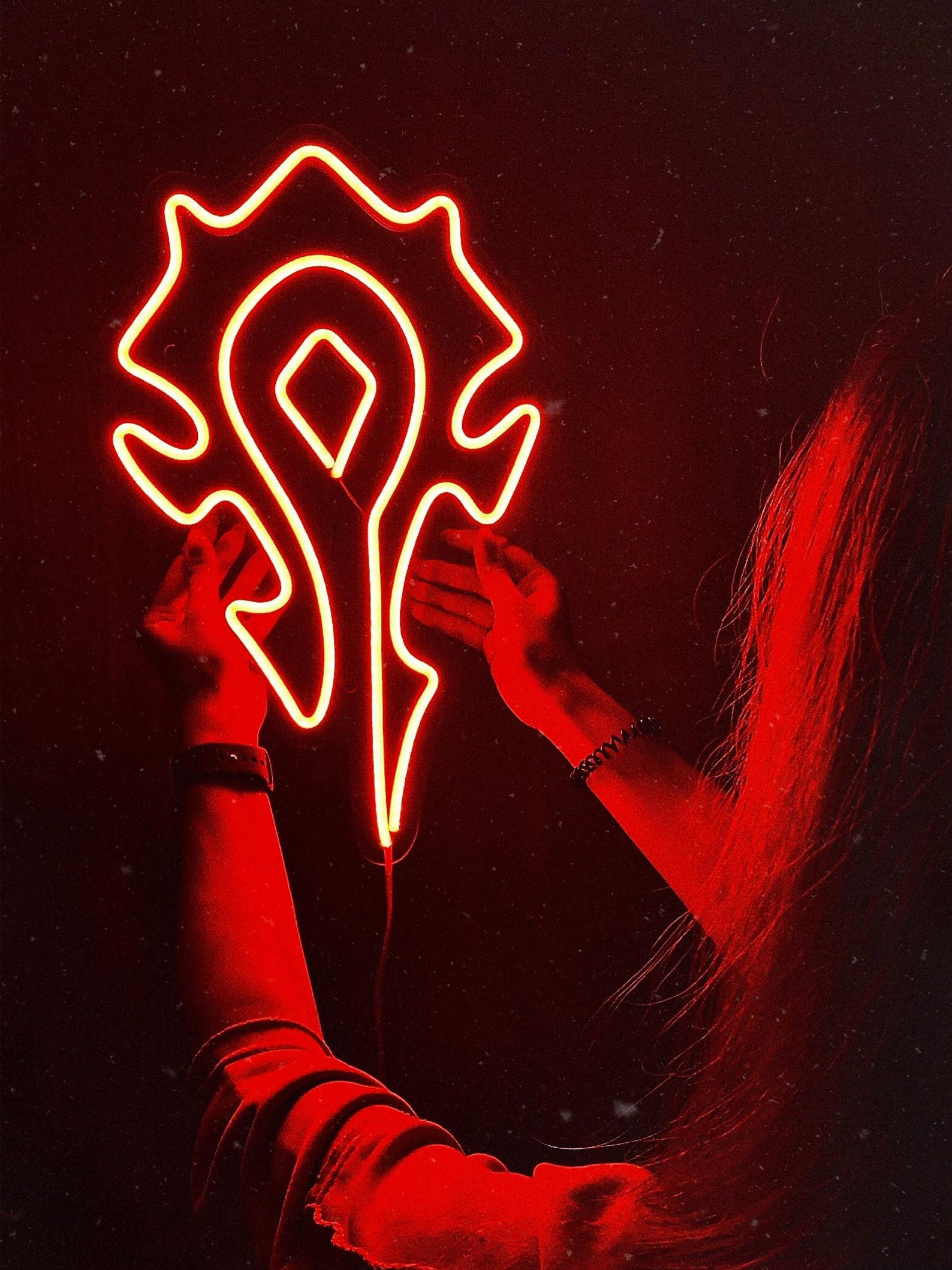 Close-up of a person holding the glowing red Horde symbol neon sign, showcasing the detailed craftsmanship and vibrant illumination.