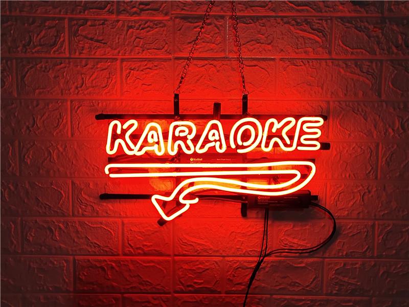 The physical 'KARAOKE' neon sign, constructed with blue and red glass tubes on a metal frame, is shown on a brick wall.