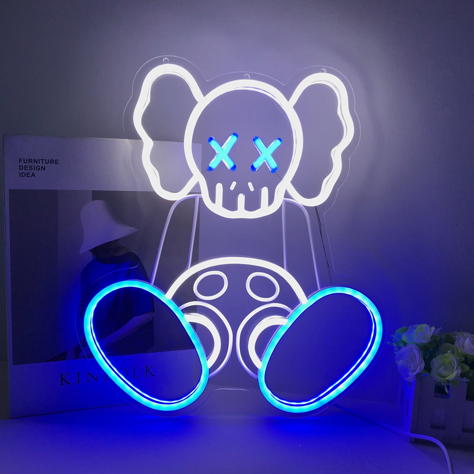 A illuminated 'Kaw Sitting Art, Anime' mini neon sign with character figure details hanging in a stylized gaming setup.