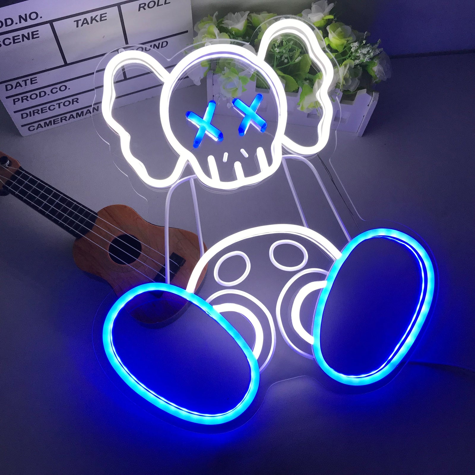 Close-up of the 'Kaw Sitting Art' mini neon sign, showing its distinct glow and acrylic backing on a desk.