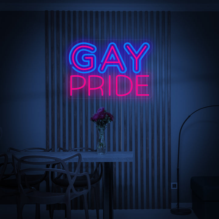 Close-up photograph of a rainbow 'LGBT Gay Pride' neon sign glowing brightly on a textured grey wall, showing the realistic tube design.