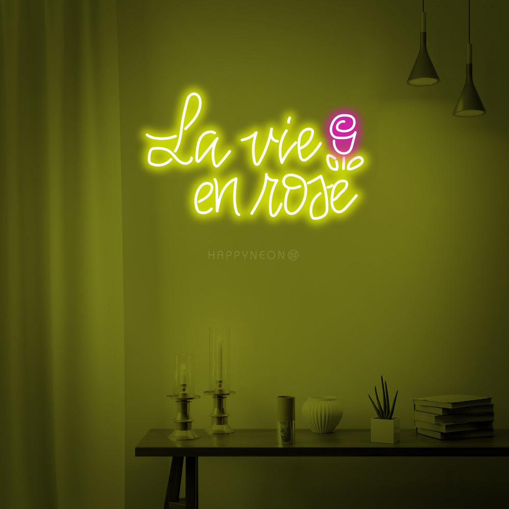 A close-up view of the 'La vie en rose' neon sign, showing the detailed glowing script and construction against a wall backdrop.