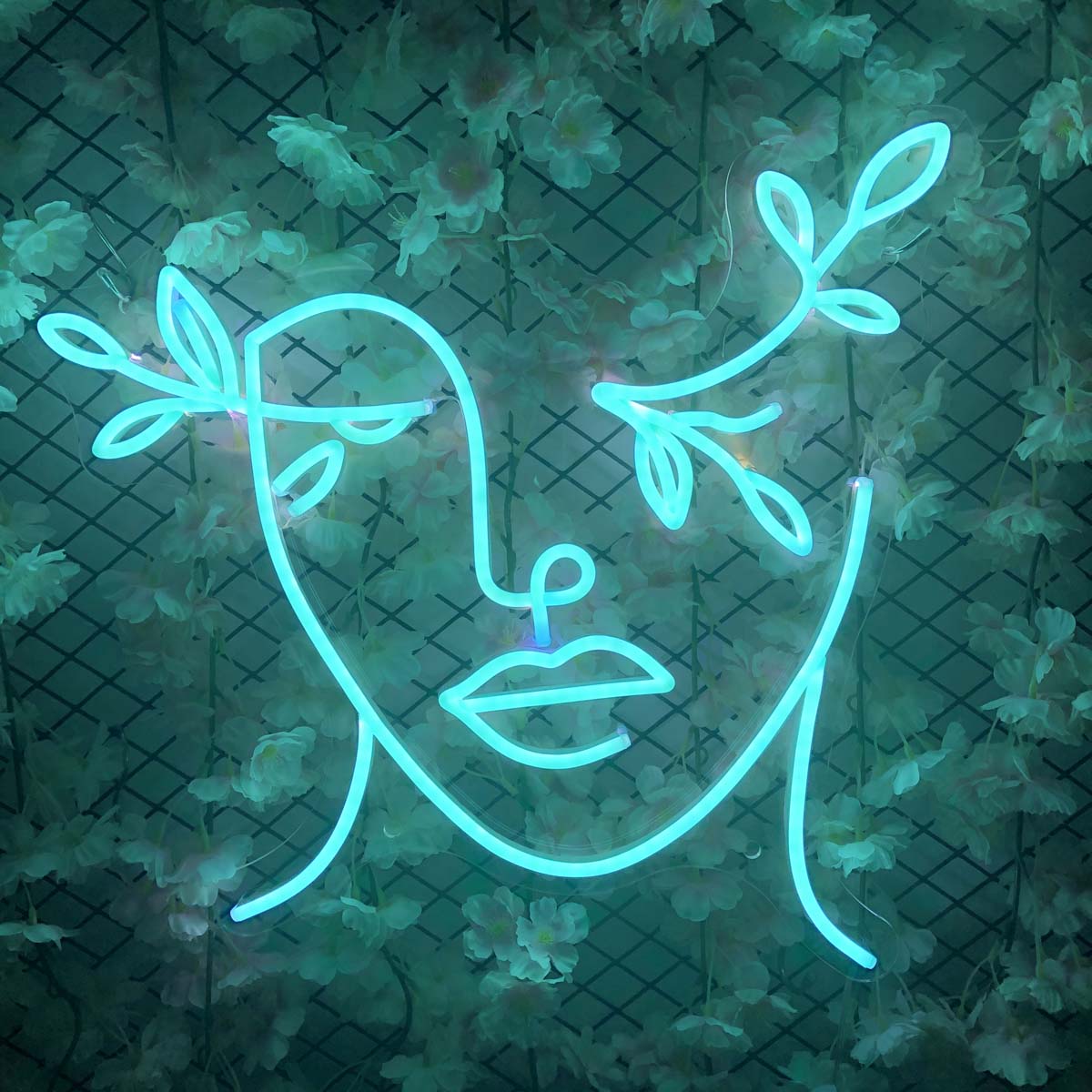 Leaves Woman Face Neon Sign against a floral background wall