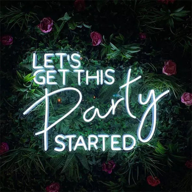 A vibrant 'Lets Get This Party Started' neon sign glowing brightly on a decorative flower wall backdrop.