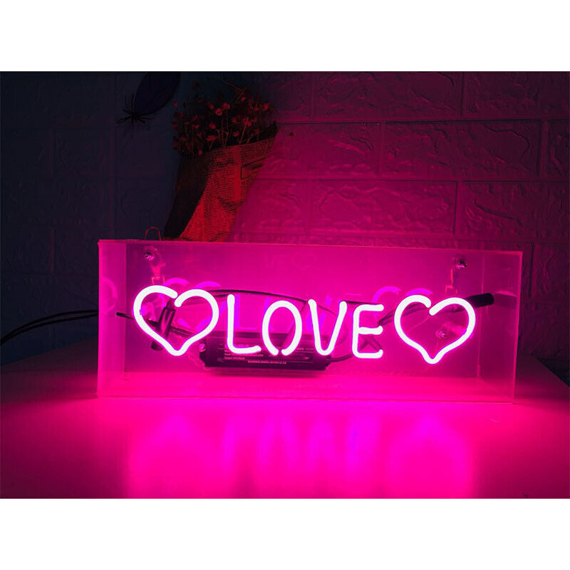 A physical table neon sign displaying the word 'Love' in a glowing red font, contained within a rectangular acrylic box with internal components visible, resting on a table.