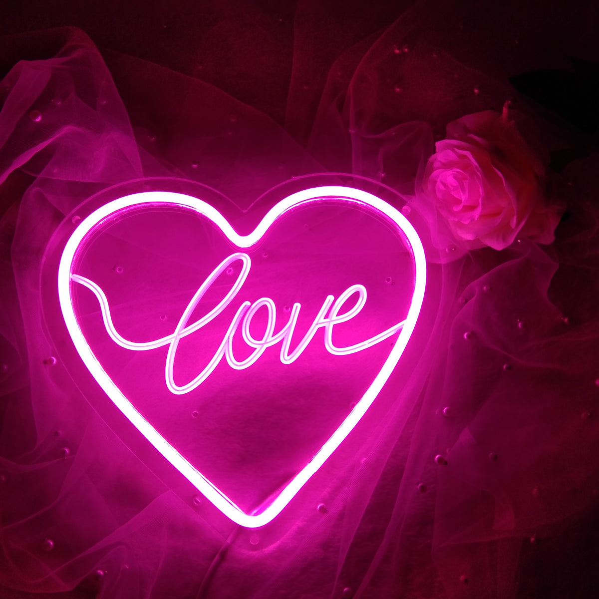 Warm glowing white LED heart neon sign on a textured pink background with a soft light overlay.