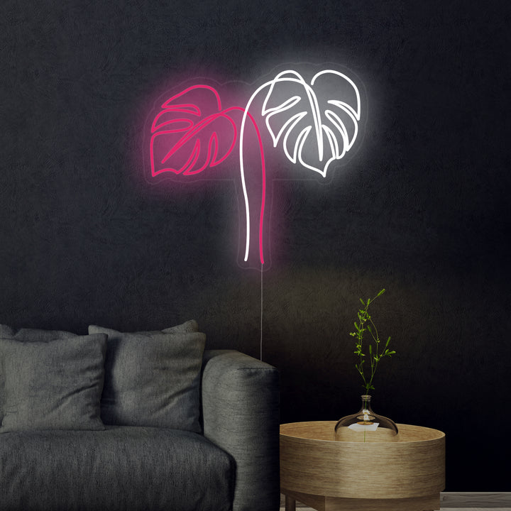 Close-up photograph of a Monstera Leaves neon sign, glowing brightly.