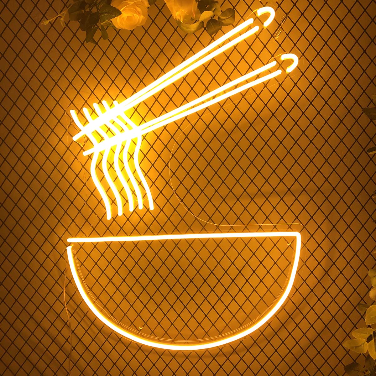 A glowing red and white neon sign spelling "Noodles" mounted on a decorative black wire mesh archway, accented with pink and white flowers and green foliage at the top.