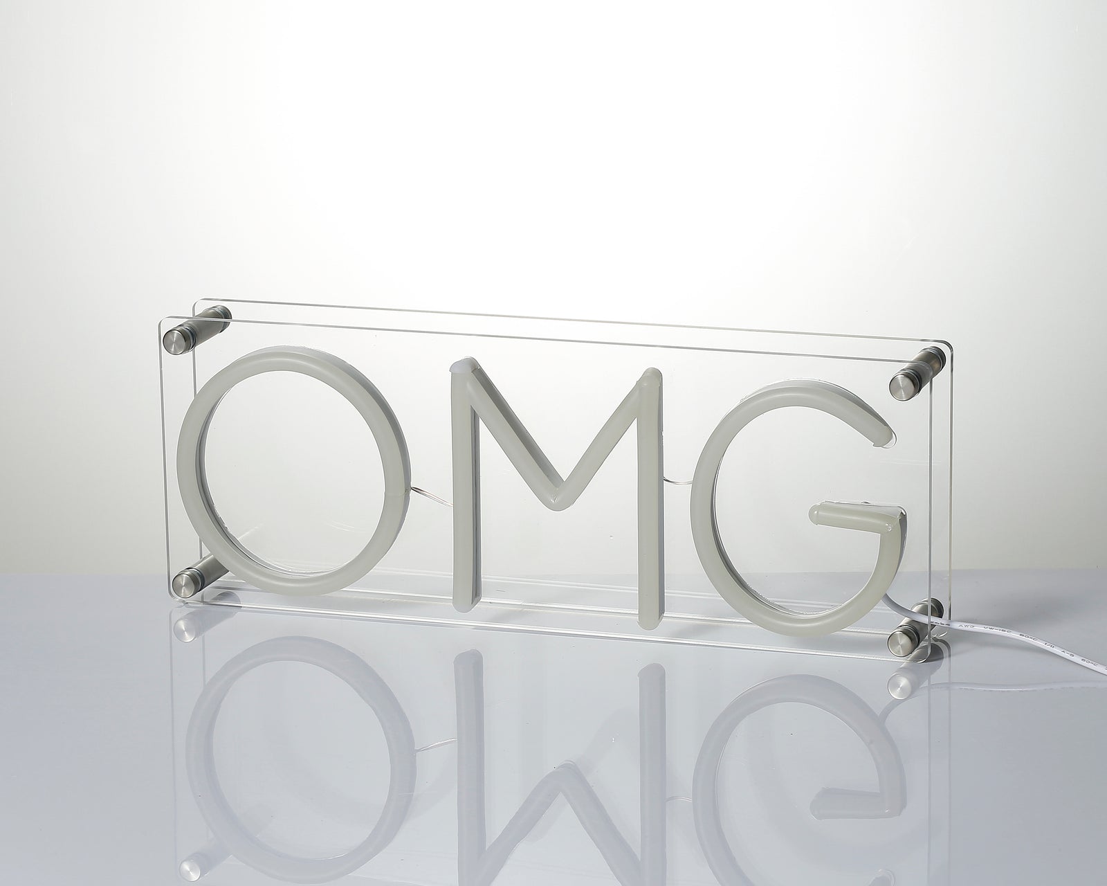 Unlit view of white 'OMG' neon sign tubing and clear acrylic mounting hardware.