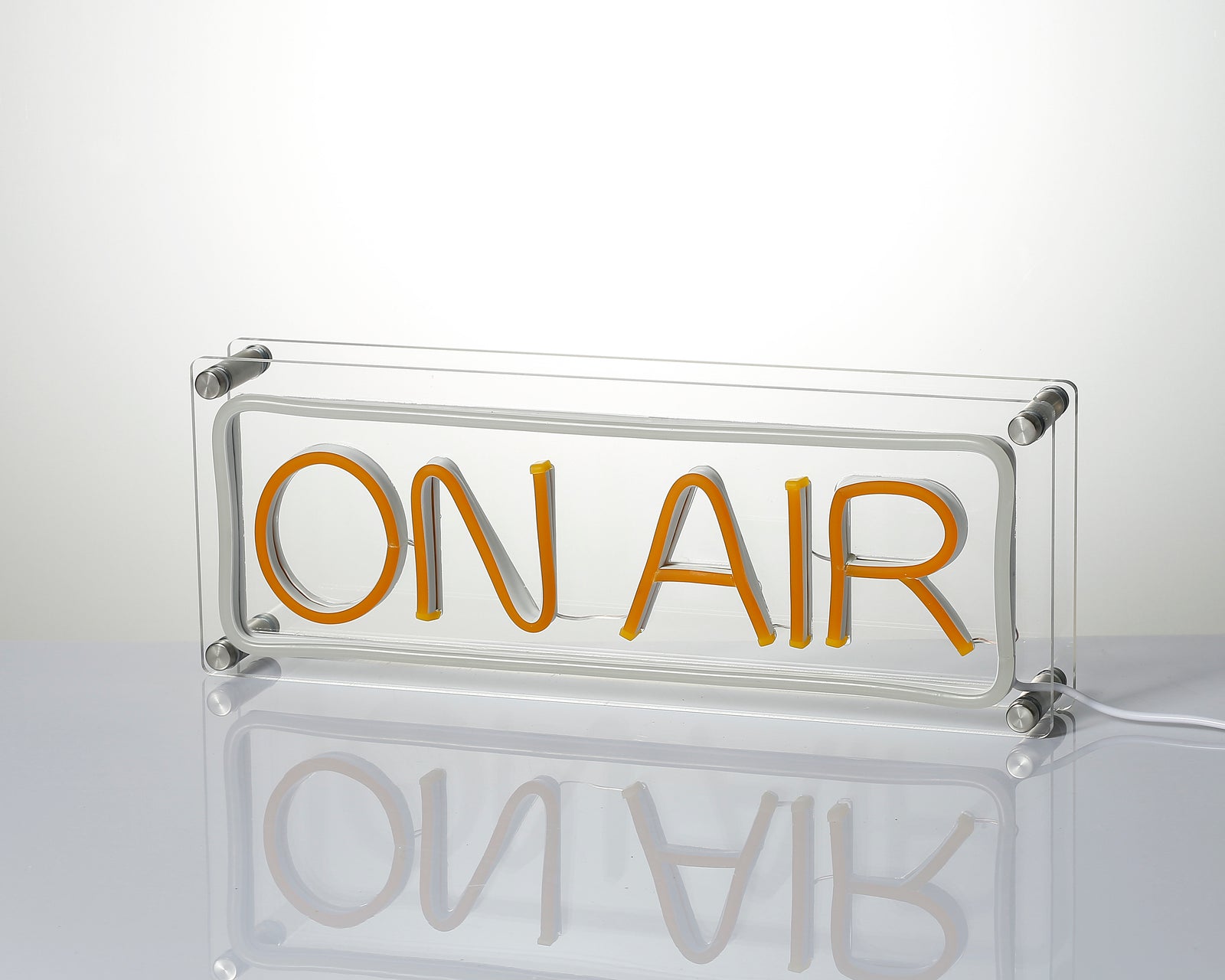 A close-up photograph of the 'ON AIR' desk neon sign showing the intricate glass tubing and clear acrylic components.