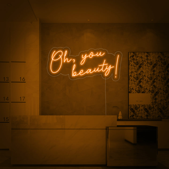 The 'Oh You Beauty' neon sign is beautifully integrated into a modern salon reception area wall.