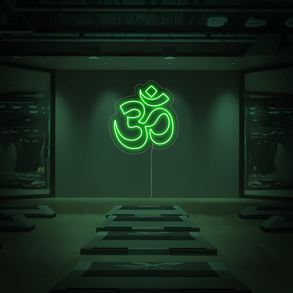 A purple Om neon sign mounted on a textured wall glows in a peaceful meditation room above a stack of yoga mats.