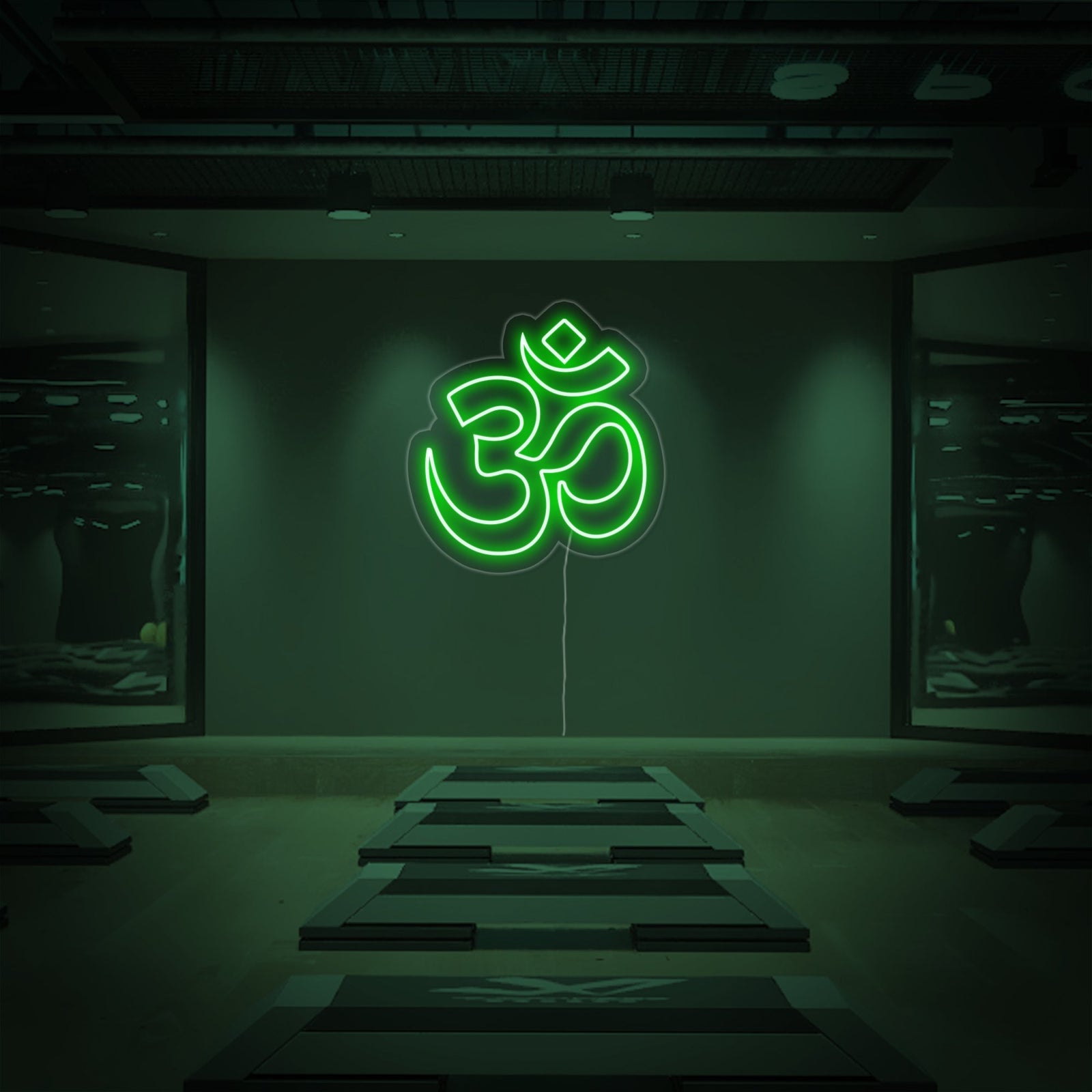 A purple Om neon sign mounted on a textured wall glows in a peaceful meditation room above a stack of yoga mats.