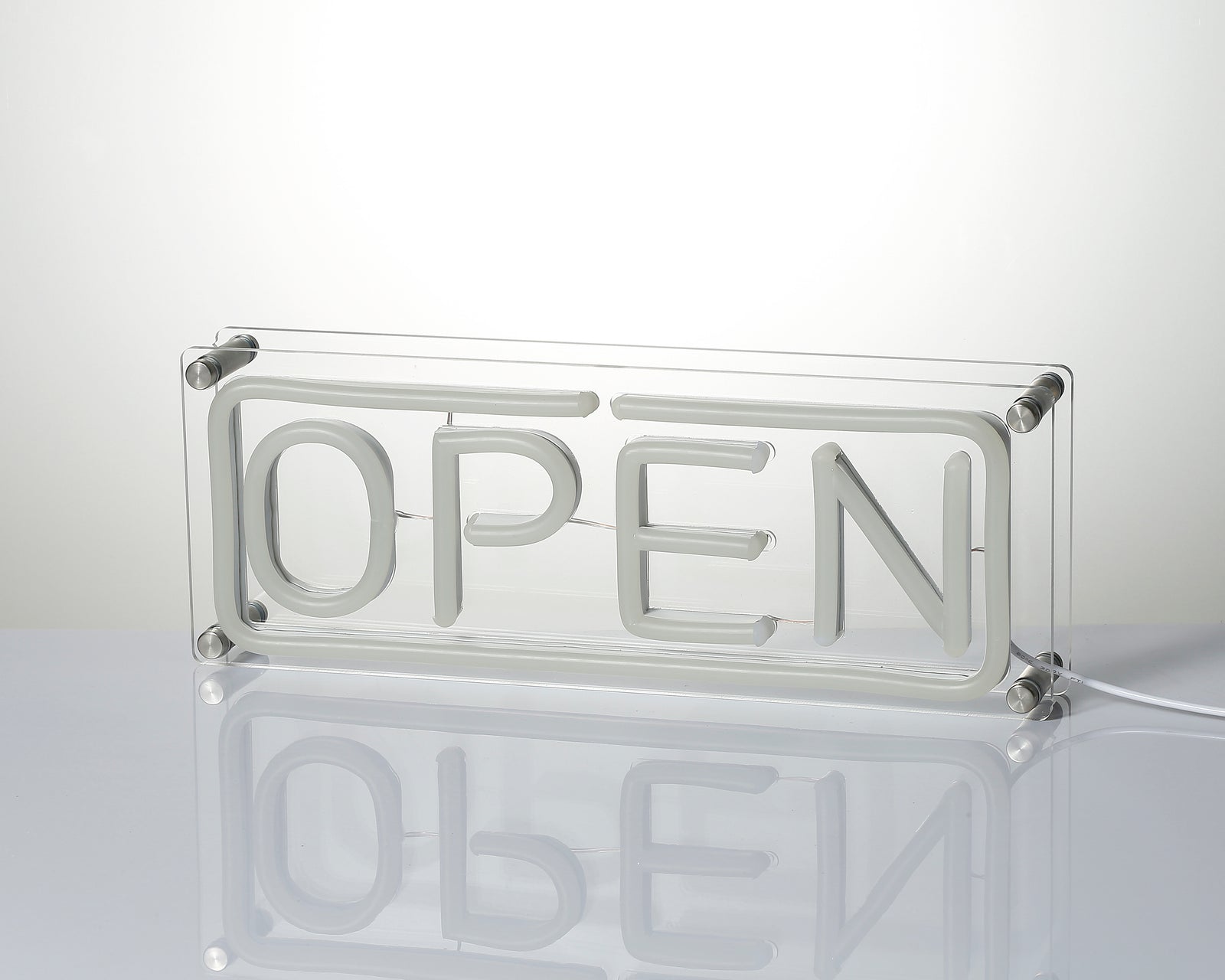 Close-up photograph of the physical 'Open' desk neon sign, showing the clear acrylic base, tubes, and reflections.