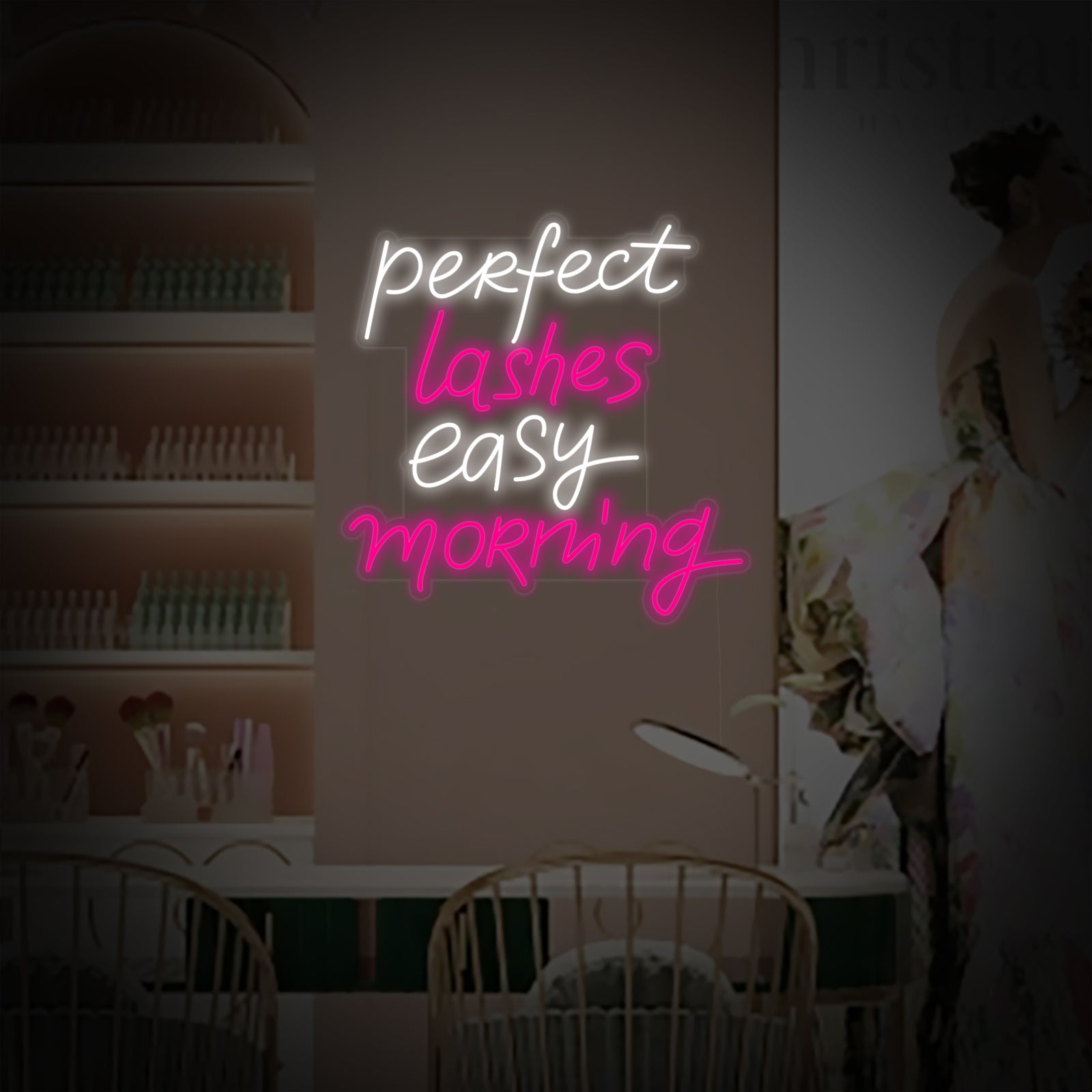 Close-up photograph of the "Perfect Lashes Easy Morning" neon sign, highlighting its elegant script and soft pink illumination against a textured wall.