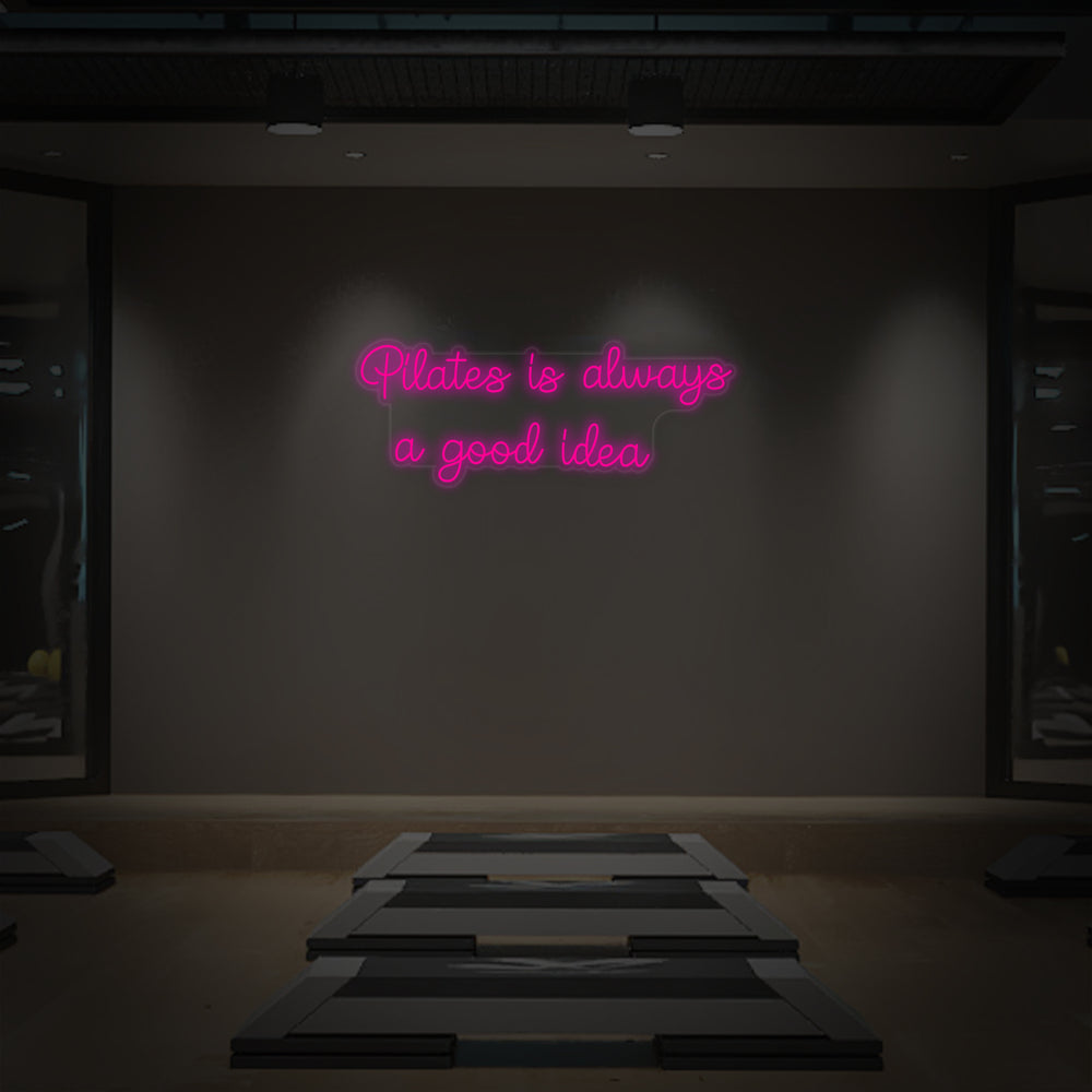 Close-up of the 'Pilates is Always a Good Idea' neon sign mounted on a clear acrylic backing.
