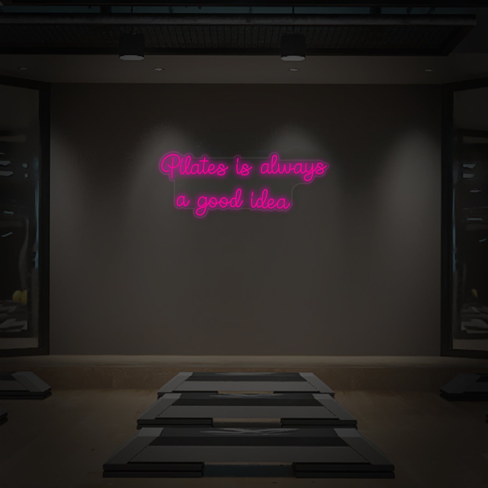 Close-up of the 'Pilates is Always a Good Idea' neon sign mounted on a clear acrylic backing.