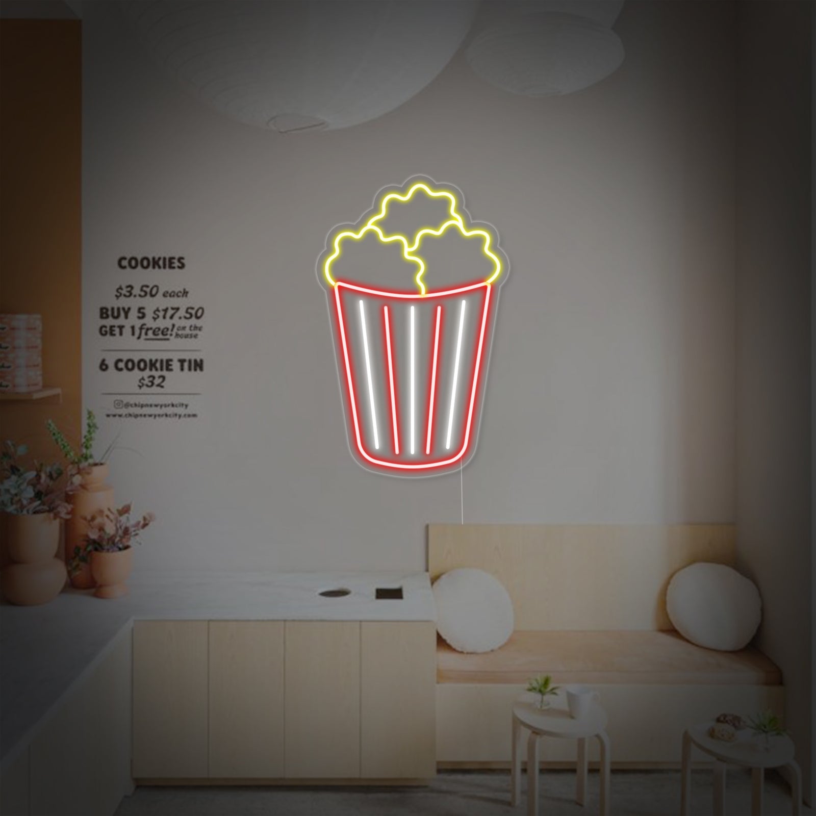 Vibrant popcorn neon sign mounted on an acrylic backboard glowing warmly in a cafe setting.