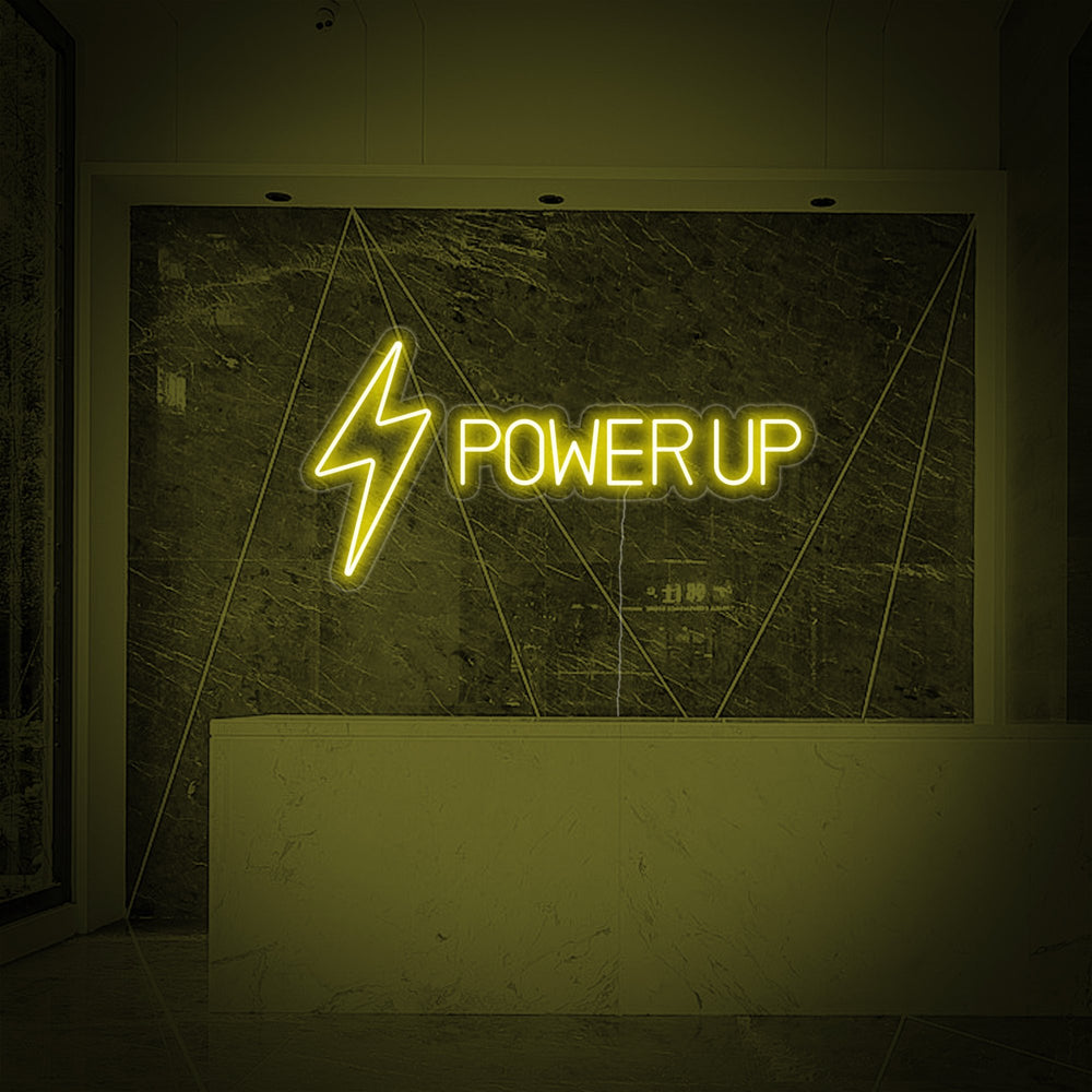 Close-up view of the 'Power Up' neon sign glowing brightly against a sophisticated marble wall in a fitness studio reception area.
