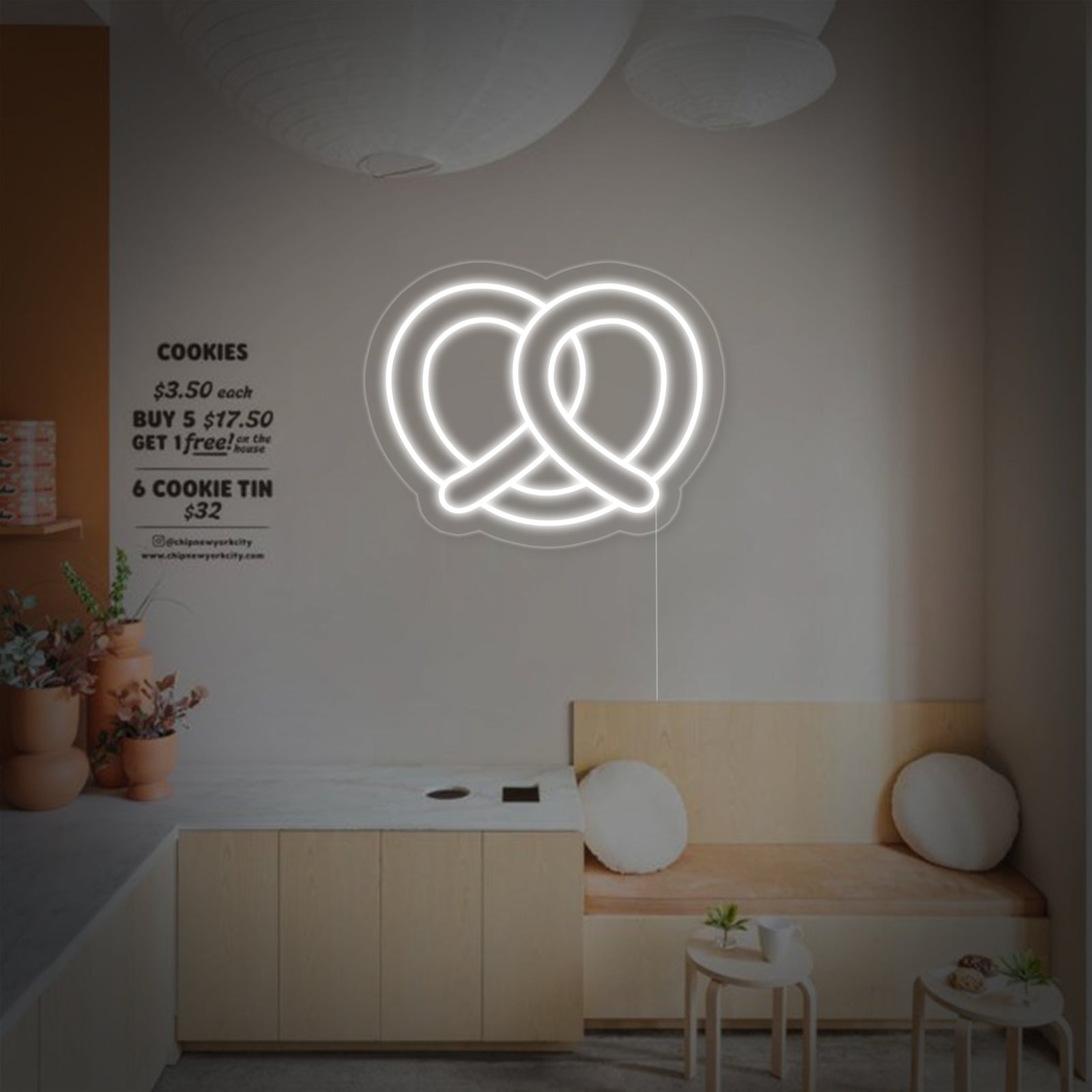 A glowing pretzel-shaped neon sign casting a bright orange light against a textured grey wall.