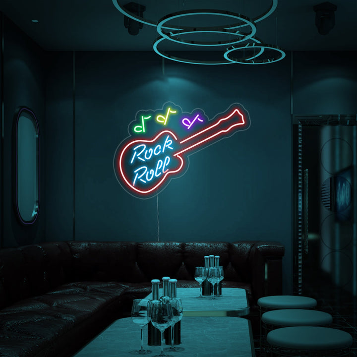 A close-up photograph of the 'Rock Roll' neon sign, showcasing the detailed glowing tubing mounted on a clear acrylic backing.