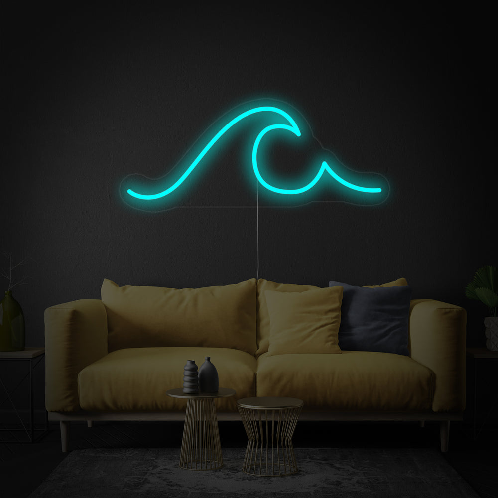 The 'Sea Wave' neon sign showing blue glowing tubing forming a wave shape, mounted on a clear acrylic backing over a textured grey surface next to a teal sofa.