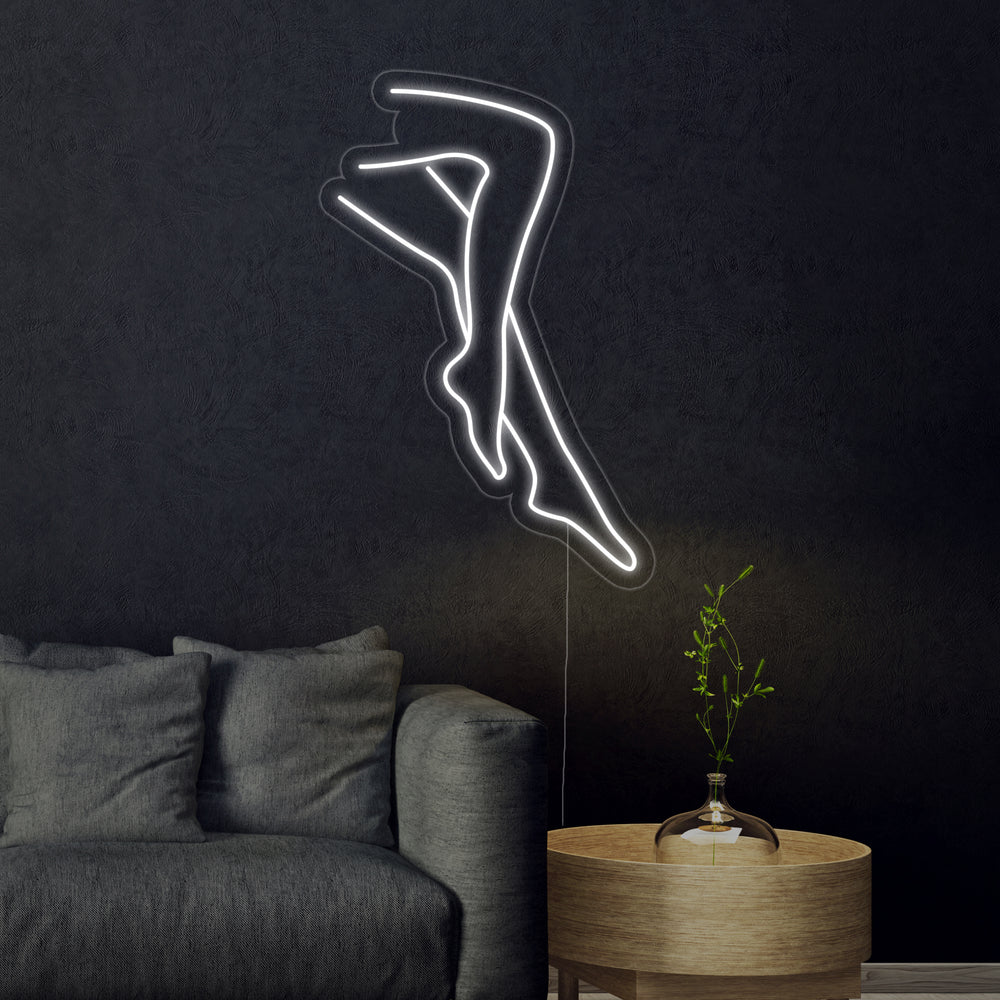 An illustrative visualization showing the "Sexy Legs Lady" neon sign with white and yellow outlines mounted above a dark modern desk and chair.