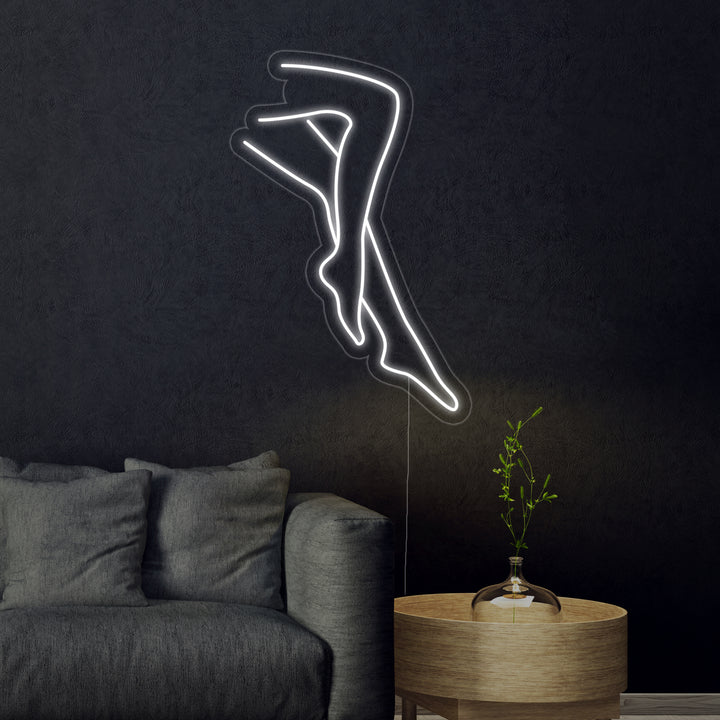 An illustrative visualization showing the "Sexy Legs Lady" neon sign with white and yellow outlines mounted above a dark modern desk and chair.