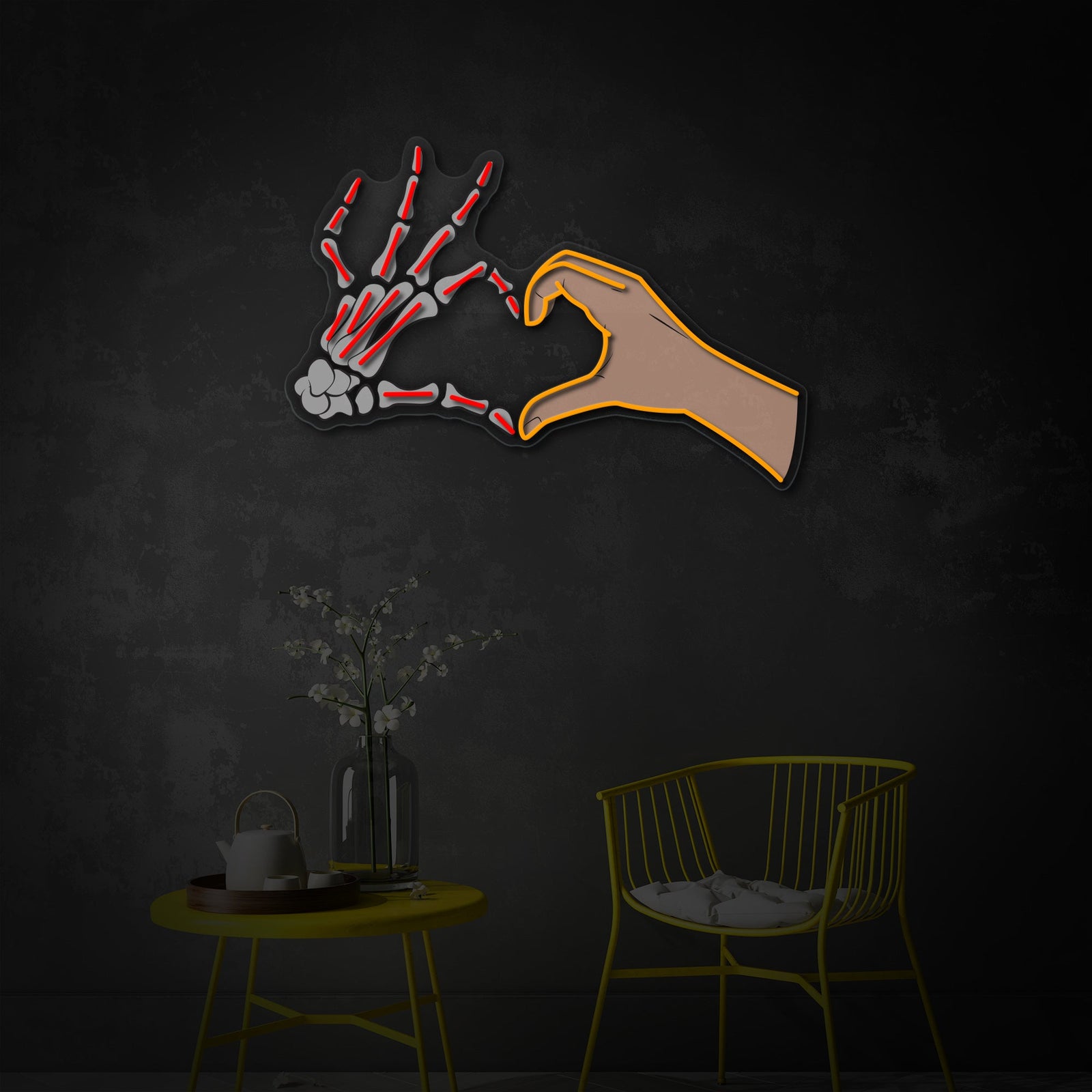 Close-up photograph of a pink glowing neon sign featuring a skull hand making a love pose, mounted on a wall in a dimly lit room