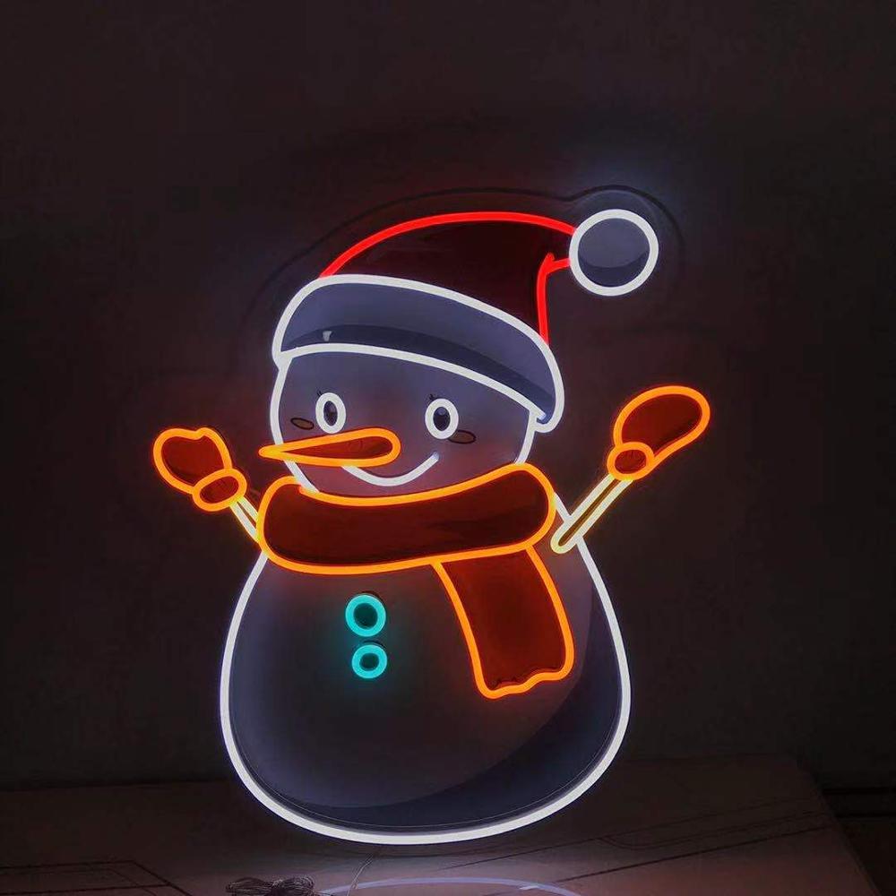A physically fabricated Snowman Neon Sign on a clear acrylic backing, showing the real bent neon tubes and wiring details, resting on a workshop surface.
