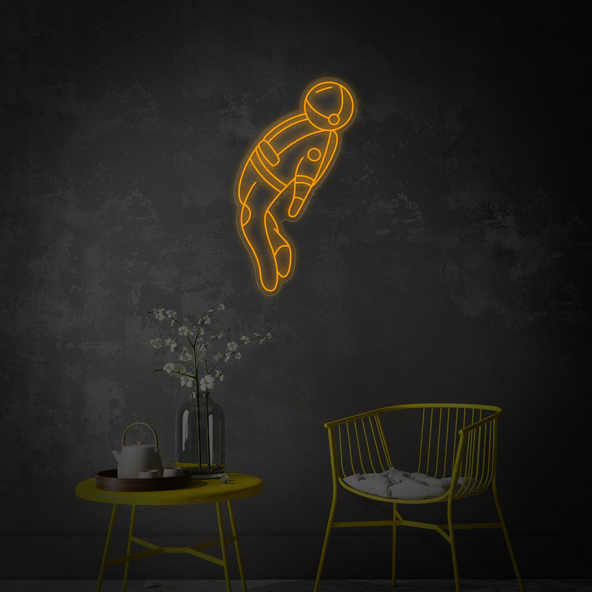 A glowing blue astronaut neon sign hangs above a small desk with a keyboard, mouse, and other items.