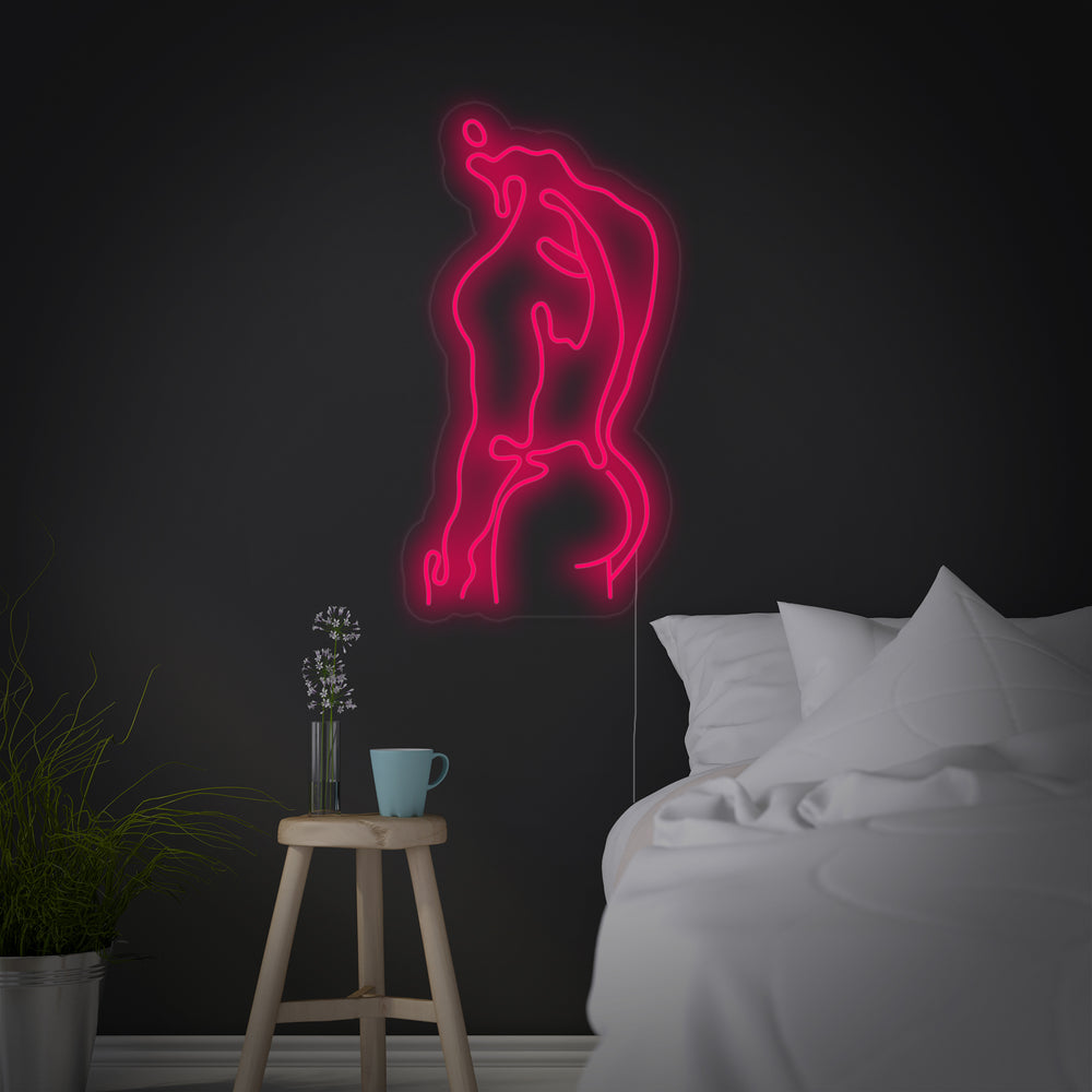 A bright red glowing neon sign depicting a muscular male physique hanging above a sofa in a modern loft apartment, highlighting its unique artistic style as a piece of glowing wall art.
