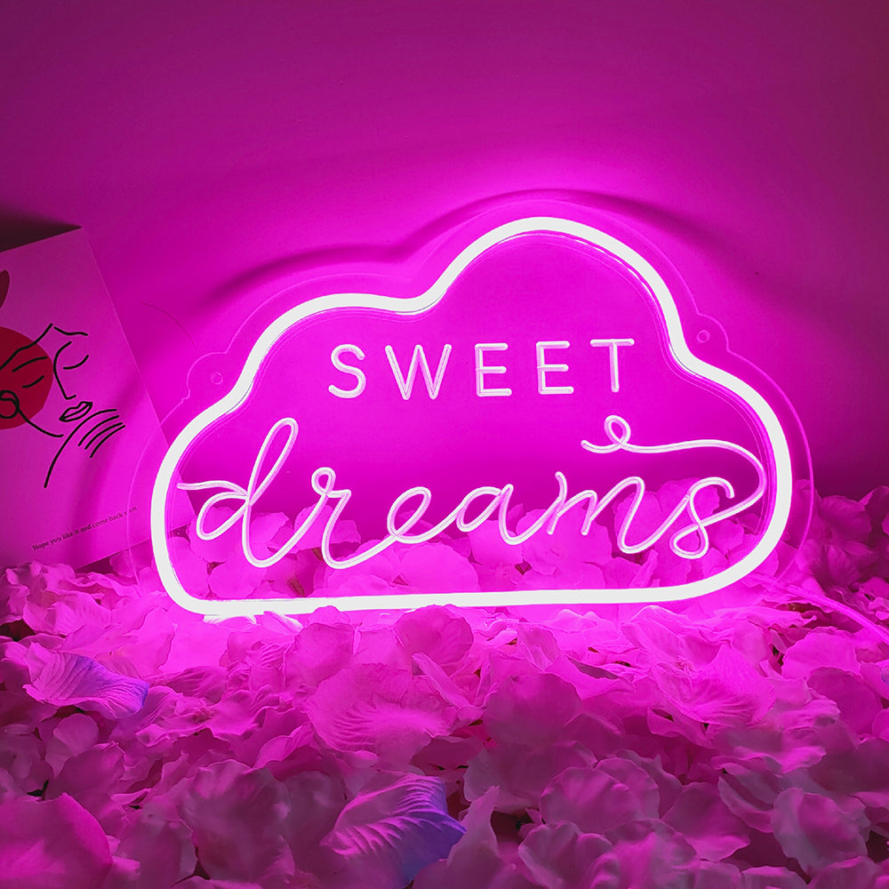 The 'Sweet Dreams' neon sign glowing in blue script, positioned above a soft-focus setting of pink and white flower petals.