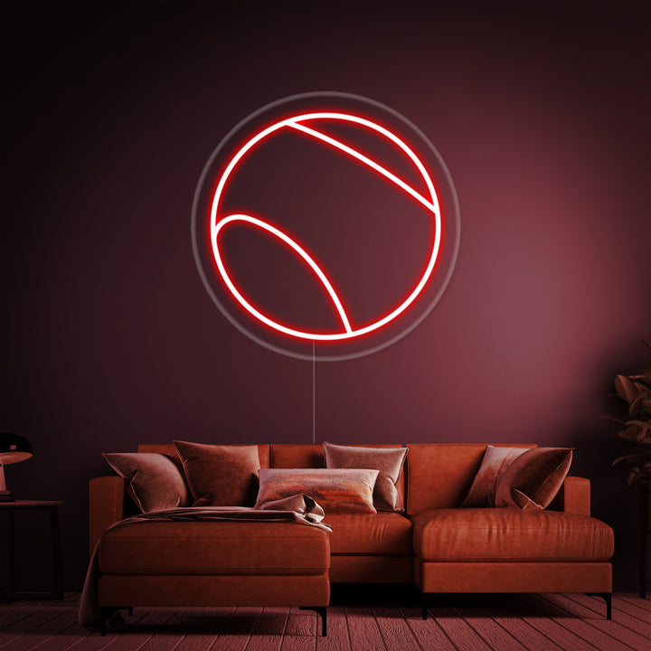 The glowing 'Tennis Ball' neon sign mounted on an acrylic backboard, casting an orange light on the wall behind it.