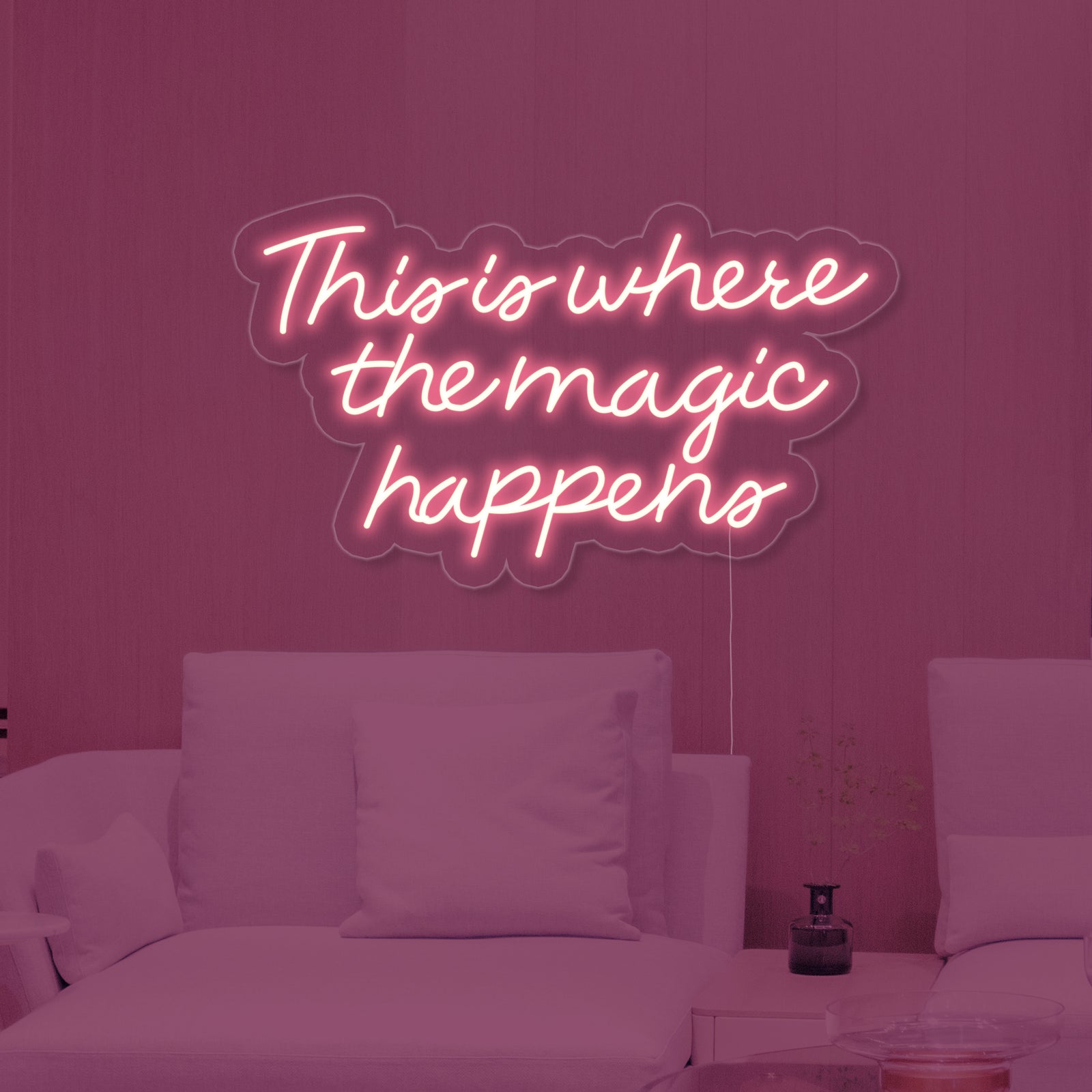 A realistic close-up view of the illuminated blue 'This is Where The Magic Happens' neon sign with clear tubing and backboard.