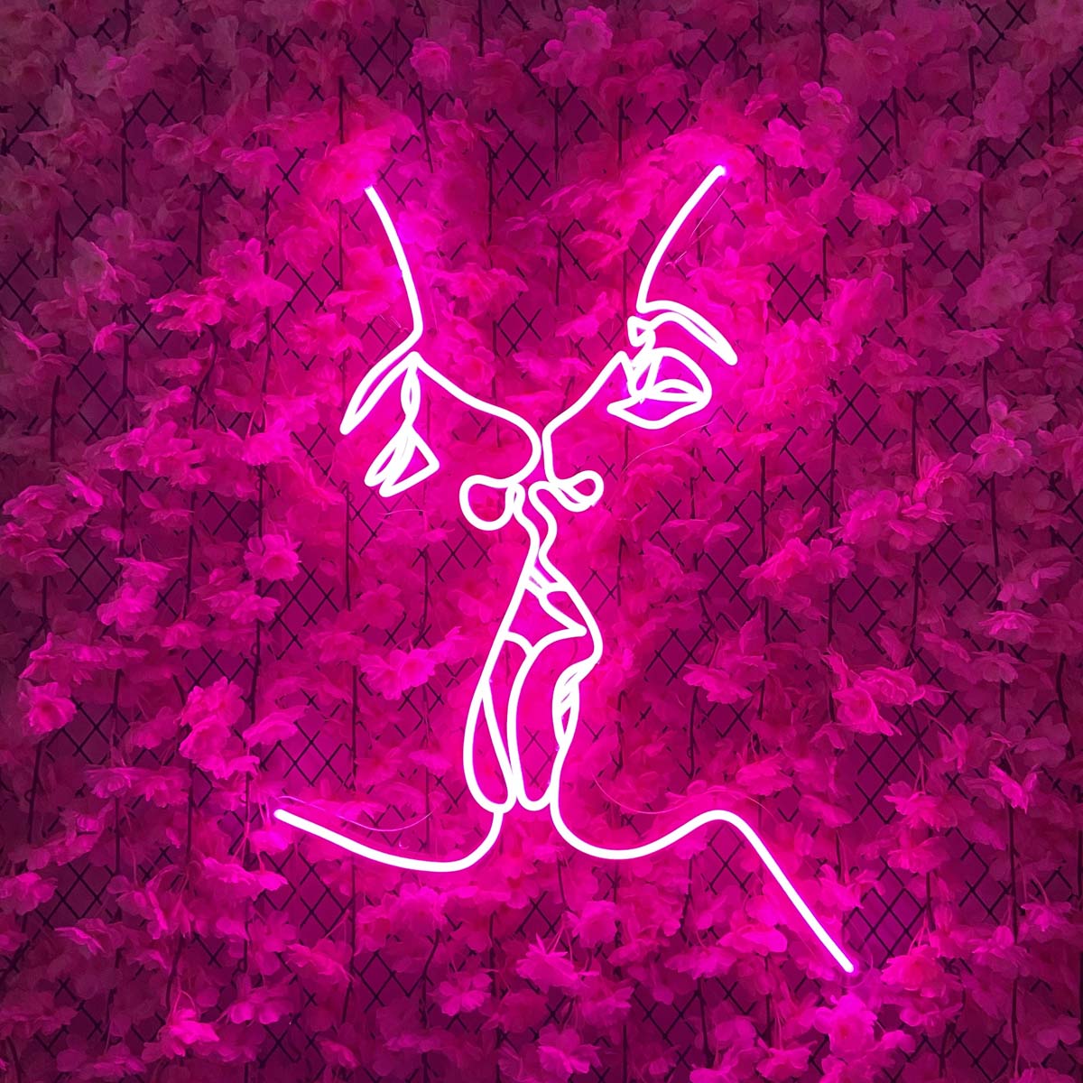 Two Faces Kiss Neon Sign glowing on a wall as contemporary art